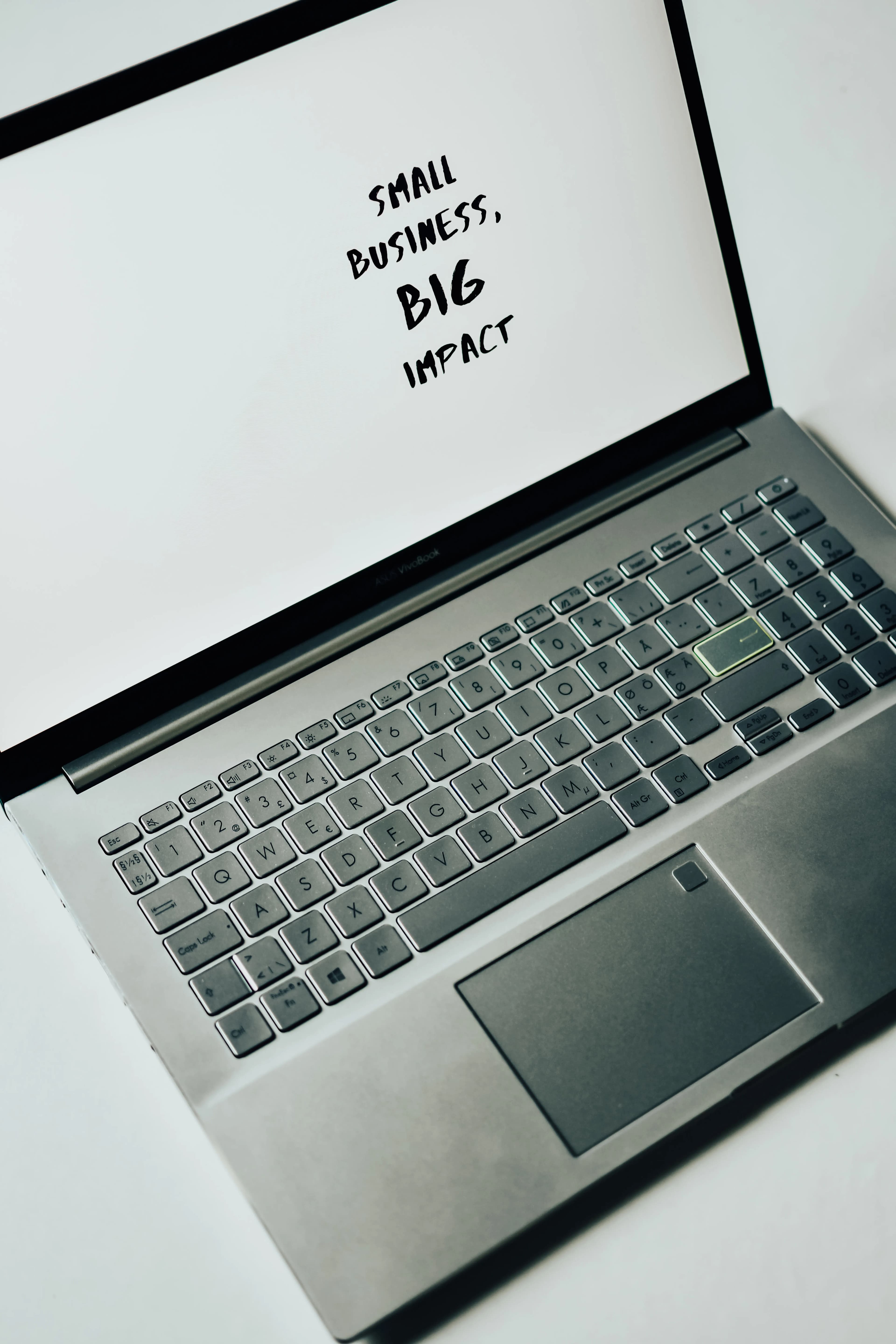 A laptop displaying the words 'small business, big impact' on its screen.