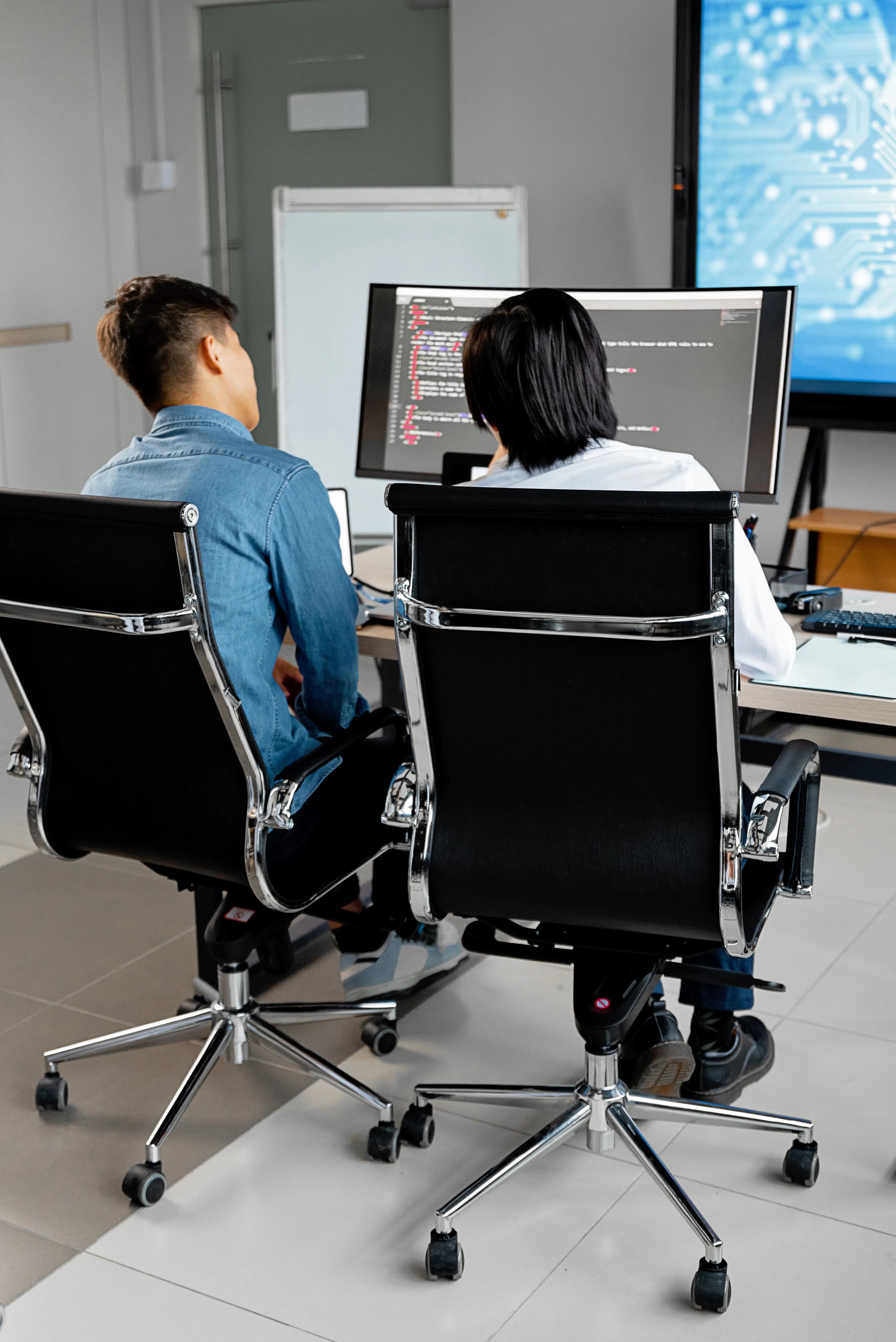 Two developers working side by side at computers during a custom software build